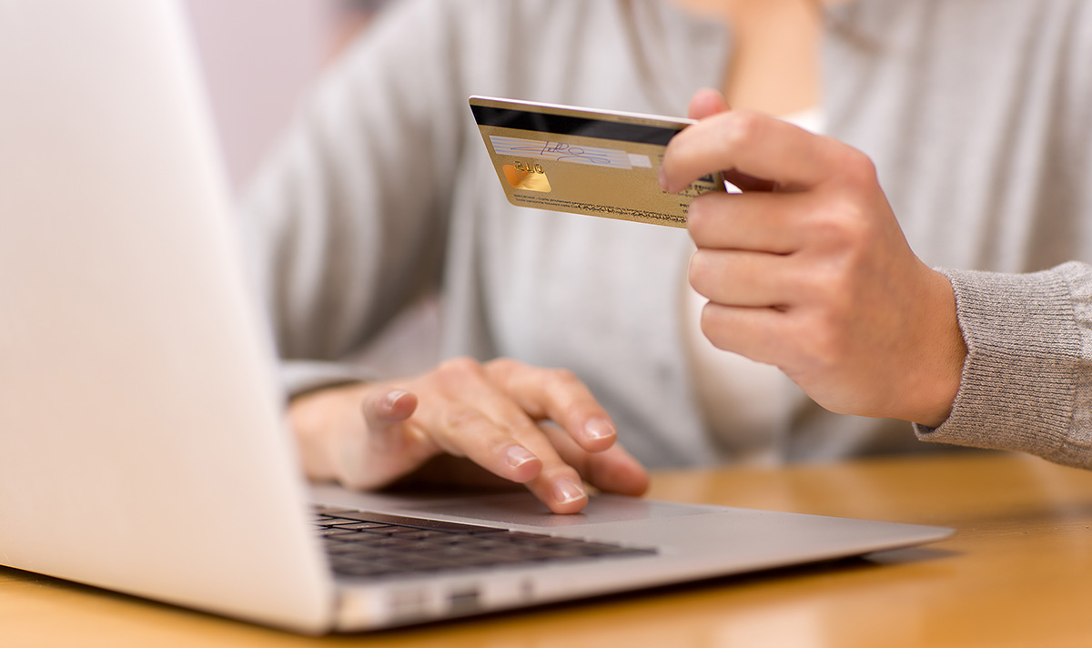 Person at a laptop holding a credit card